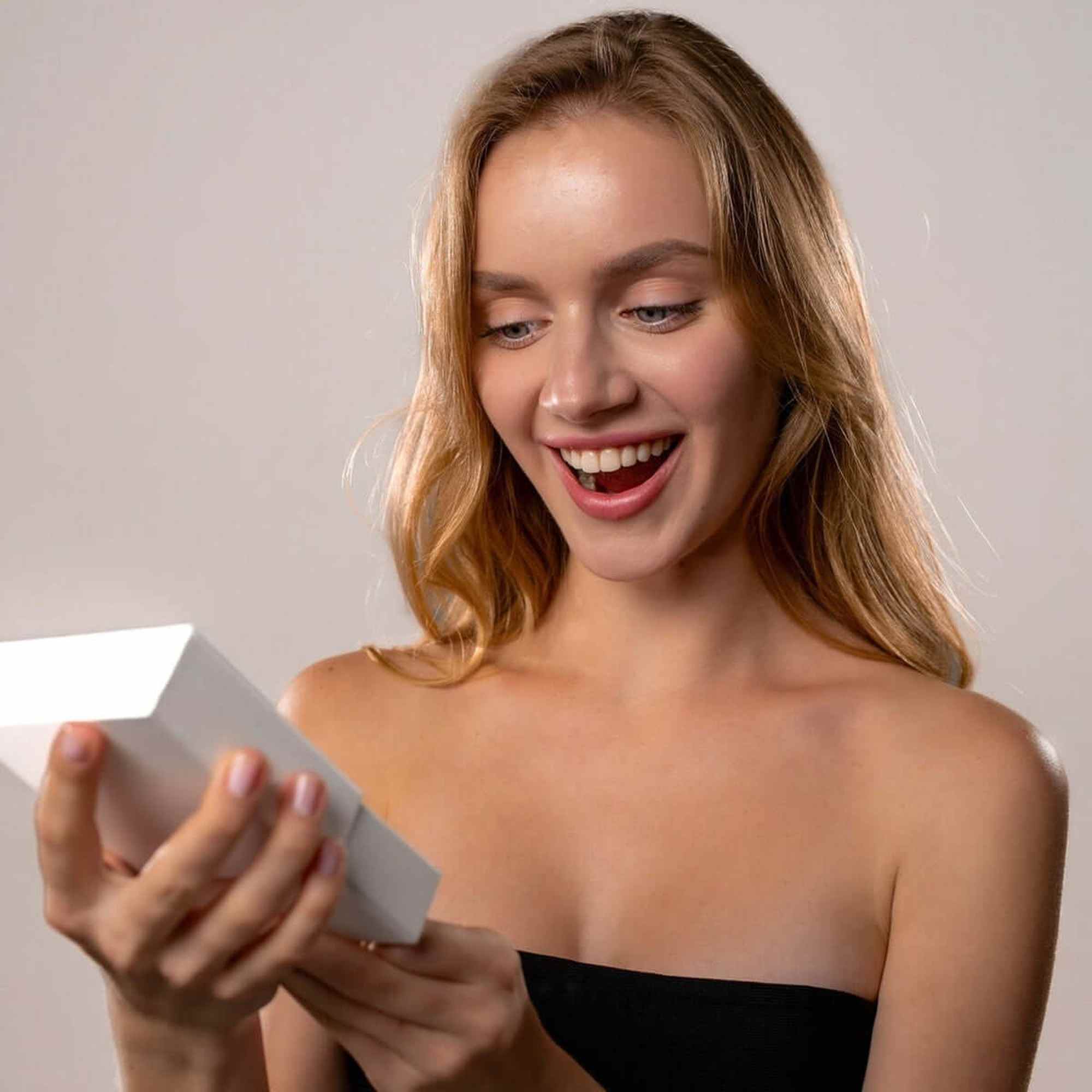 Excited woman opening a gift box, showcasing the joy of receiving a Love Photo Necklace from Brother & Sisters.