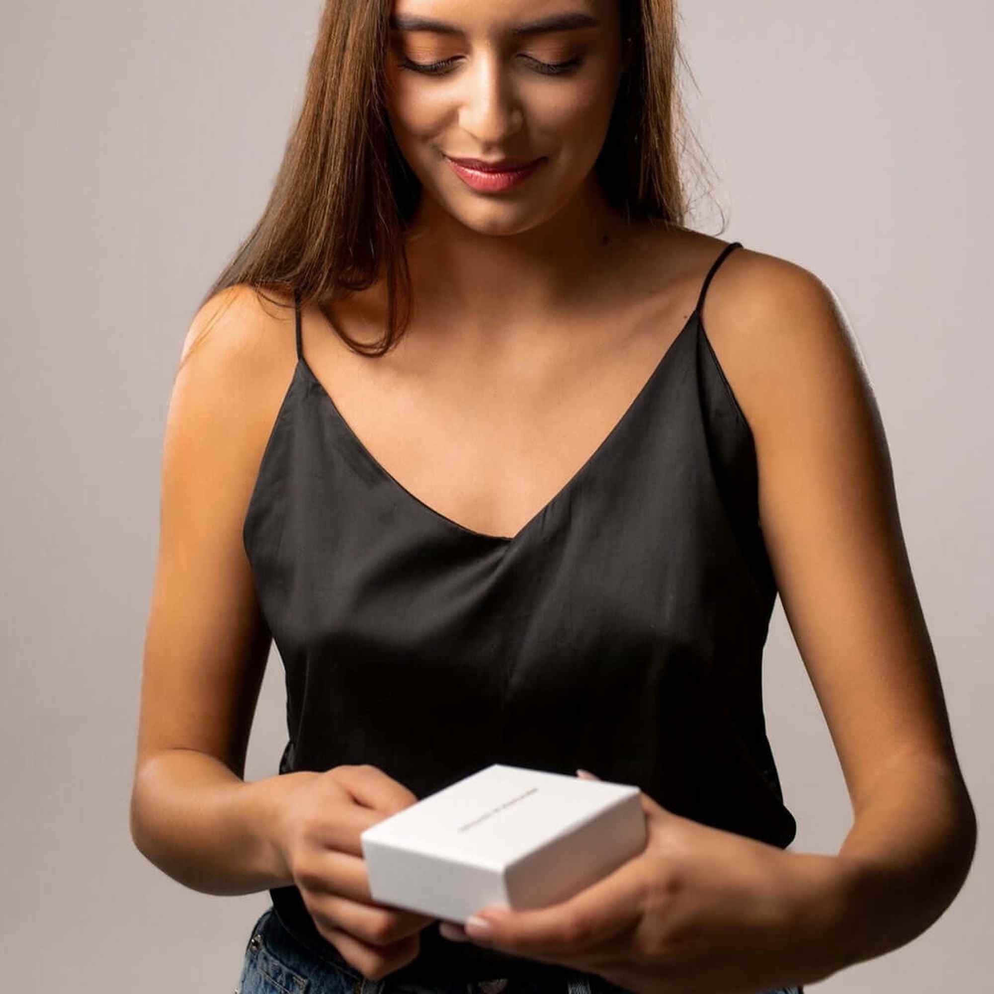 Woman opening a gift box, excited to reveal the Love Photo Necklace by Brother & Sisters.