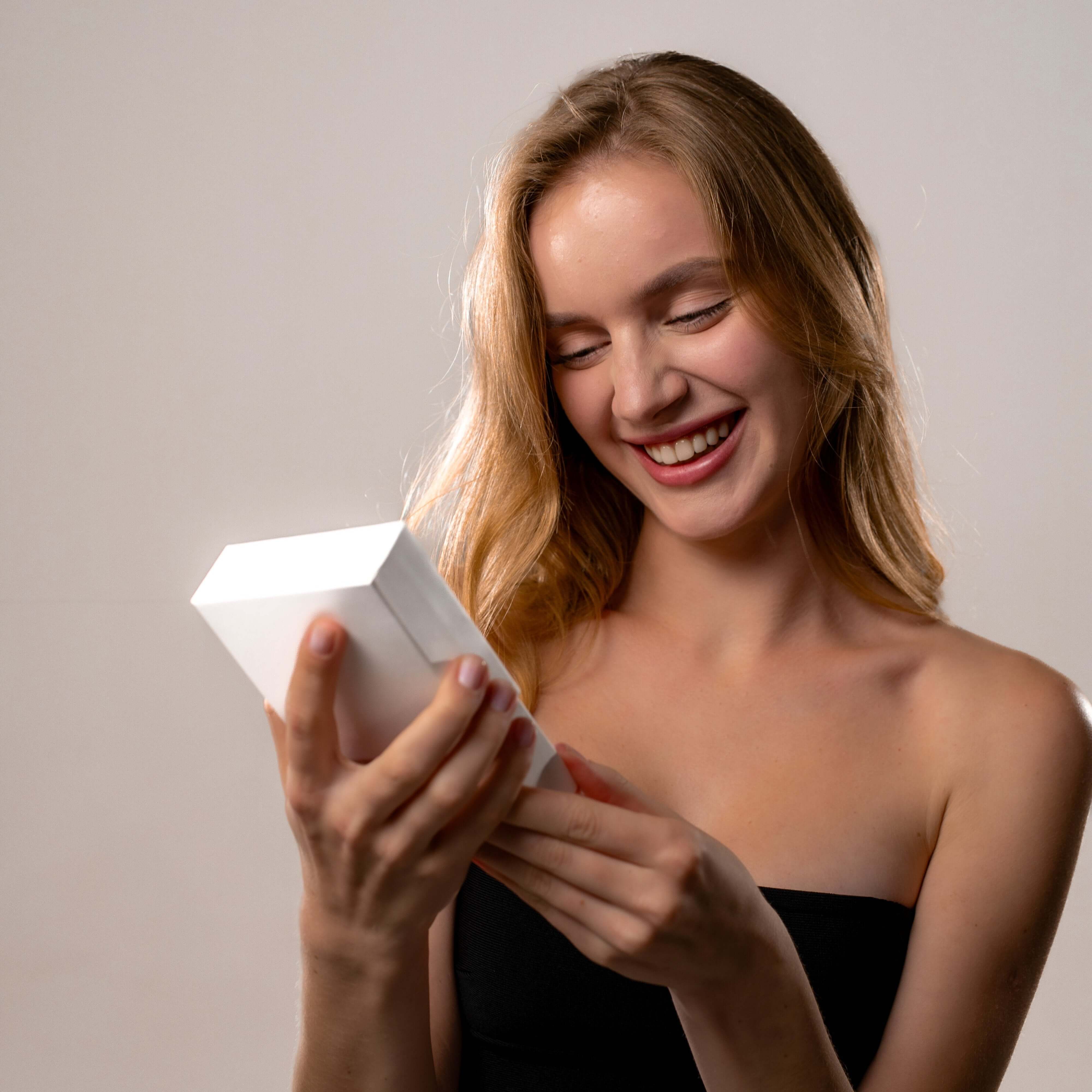 A woman happily holding a gift box, representing the joy of receiving the Angel Photo Bracelet from Brother & Sisters.