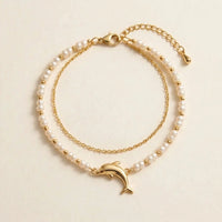 Thumbnail for Pearl Dolphin Anklet Set laid flat, showing the pearl strand, the fine gold cable chain and the gold dolphin charm, by Brother & Sisters.