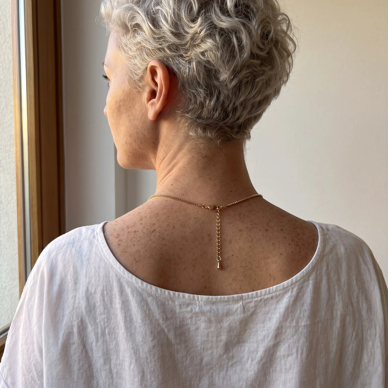 Back of the neck of a grey-haired woman showing the clasp and extension chain of the gold clover photo necklace | SKU: TPH-CLVN-GOLD