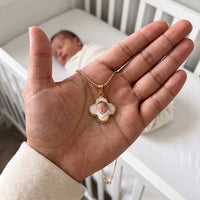 Thumbnail for The gold clover photo pendant in an open palm, real small size, a newborn sleeping in the crib behind | SKU: TPH-CLVN-GOLD