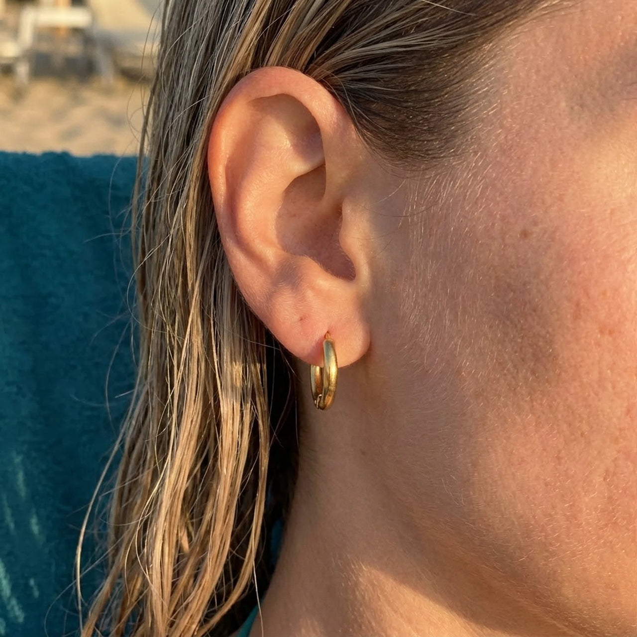Tiny Huggie Hoops in Gold, close-up on the earlobe | SKU: 41002-gold