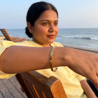 Thumbnail for Travel To Feel Alive bracelet in gold worn during a relaxed moment | SKU: ttfa-g
